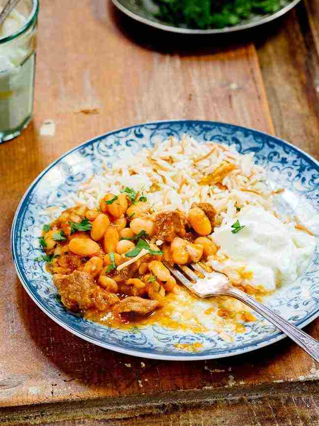 خورش لوبیا سفید ترکی با برنج و ماست در بشقاب آبی طرح دار نیمه خورده خورش لوبیا سفید ترکی با برنج و ماست در بشقاب آبی طرح دار نیمه خورده